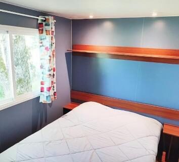 Chambre avec lit et fenêtre au ZEcamping 3 étoiles parc aquatique vacances 100 % nature
