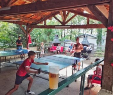 Abri en bois avec tables de ping pong et joueurs au ZEcamping 3 étoiles parc aquatique vacances 100 % nature