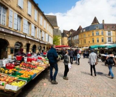 Place pavée avec étals de marché et passants au ZEcamping 3 étoiles parc aquatique vacances 100 % nature