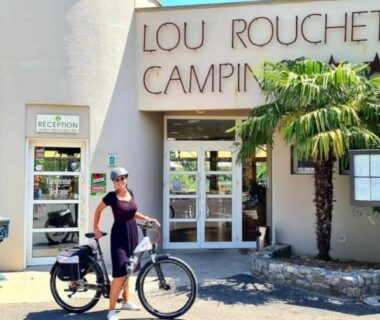 Façade et entrée avec cycliste et palmiers au camping Lou Rouchetou