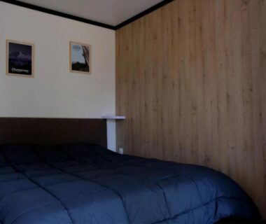 Chambre avec lit et lambris en bois au ZEcamping 3 étoiles pet friendly restaurant avec une vue panoramique