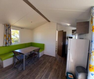 Intérieur de mobil-home coin repas avec banquette verte dans le ZEcamping 3 étoiles piscine chauffée club enfant dog friendly