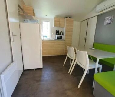Intérieur du locatif avec kitchenette table banquette et clim au ZEcamping 3 étoiles piscine chauffée dog friendly locatif BBQ clim
