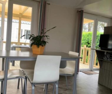 Intérieur coin repas avec table et baie vitrée du ZEcamping 3 étoiles
