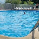 Piscine extérieure avec échelle et transats au ZEcamping 3 étoiles piscine chauffée et pataugeoire pet friendly