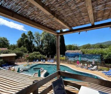 Terrasse couverte avec vue sur la piscine et transats du ZEcamping 3 étoiles