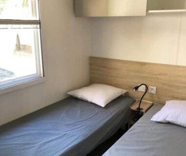 Chambre avec deux lits et lampe près de la fenêtre au ZEcamping 4 étoiles 2km plage piscine chauffée
