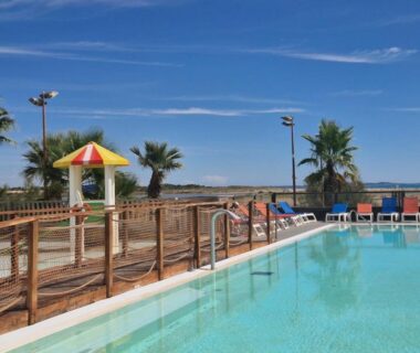Piscine avec transats et plage en arrière plan au ZEcamping 4 étoiles Accès direct plage
