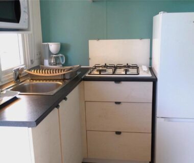 Coin cuisine équipée avec plaque et réfrigérateur dans le mobil home ZEcamping 4 étoiles TV Clim