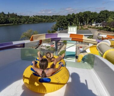 Toboggan aquatique avec bouée et personnes surplombant un lac au ZEcamping 4 étoiles Bord de Lac