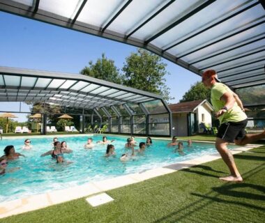 Piscine couverte avec enfants jouant et personne sautant au ZEcamping 4 étoiles Familial Parc Aqua Esprit Champêtre Dog Friendly