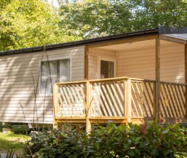 Mobil home avec terrasse en bois au milieu des arbres du ZEcamping 4 étoiles Familial