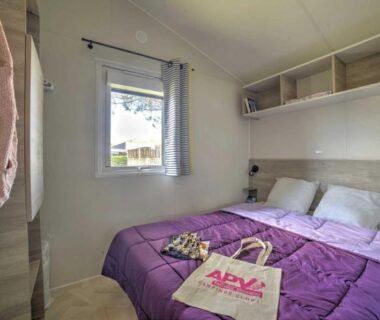 Chambre avec lit double et couette violette dans le mobil-home ZEcamping
