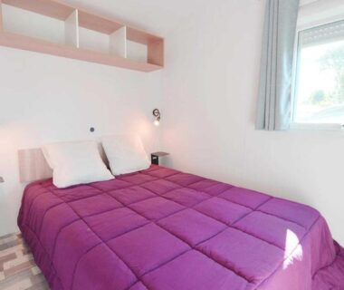 Chambre avec lit et couette violette dans le camping ZEcamping 4 étoiles