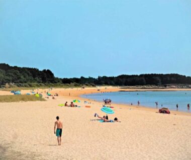Plage de sable avec baigneurs et parasols au ZEcamping 4 étoiles