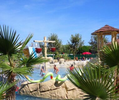 Piscine extérieure avec toboggans et palmiers au ZEcamping 4 étoiles Top Parc Aqua