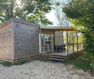 Terrasse couverte avec table et chaises devant mobil-home en bois au ZEcamping 4 étoiles