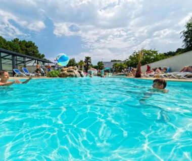 Piscine extérieure avec baigneurs et bouée au camping ZEcamping 4 étoiles animé parc aquatique pet friendly sauna