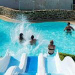 Piscine extérieure avec toboggans et baigneurs au ZEcamping 4 étoiles animé parc aquatique pet friendly sauna