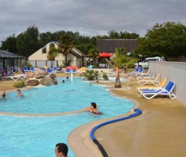 Piscine extérieure avec transats et palmiers au ZEcamping 4 étoiles animé parc aquatique pet friendly sauna