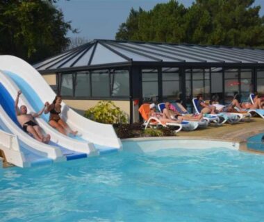 Piscine extérieure avec toboggans et chaises longues au camping ZEcamping 4 étoiles