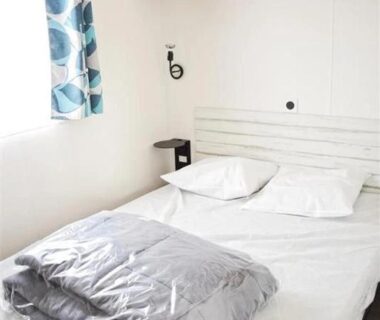 Chambre avec lit double et rideau bleu dans le ZEcamping 4 étoiles