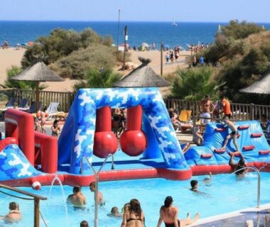 Piscine avec parcours gonflable et plage en arrière plan au ZEcamping 4 étoiles chiens acceptés