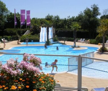 Piscine extérieure avec toboggans et transats au ZEcamping 4 étoiles familial avec étang de pêche et piscine chauffée