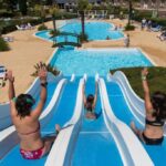 Piscine extérieure avec toboggans et transats au ZEcamping 4 étoiles familial