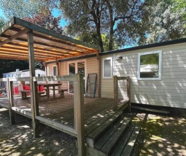 Terrasse couverte et mobil-home sous arbres au ZEcamping 4 étoiles familial