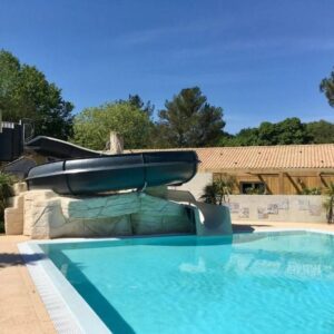 Piscine extérieure avec toboggan et bâtiment en arrière plan au ZEcamping 4 étoiles familial piscine couverte