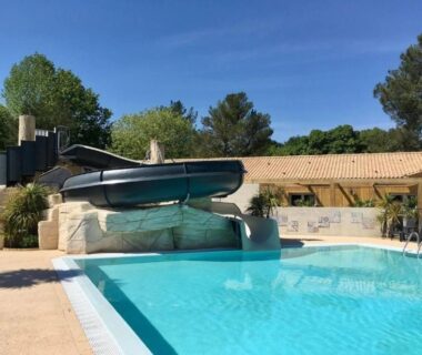 Piscine extérieure avec toboggan et bâtiment en arrière plan au ZEcamping 4 étoiles familial piscine couverte
