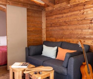 Salon en bois avec canapé et guitare dans le ZEcamping