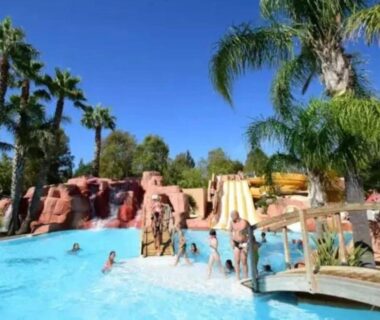 Piscine avec toboggans et palmiers au ZEcamping 4 étoiles parc aquatique hammam et restaurant