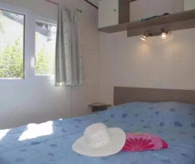 Chambre avec lit et chapeau sur le lit au ZEcamping 4 étoiles parc aquatique hammam et restaurant