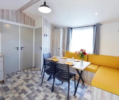 Intérieur du mobil-home coin repas banquette jaune et table au ZEcamping 4 étoiles verdoyant MH Climatisé