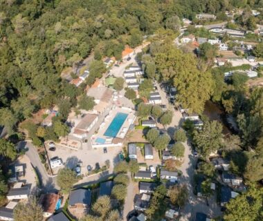 Vue aérienne du camping avec piscine entourée d'arbres au ZEcamping 4 étoiles verdoyant