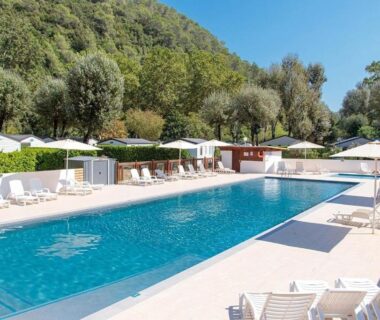 Piscine extérieure bordée de transats au camping ZEcamping 4 étoiles verdoyant