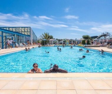 Piscine extérieure avec baigneurs et transats au ZEcamping 5 étoiles Parc Aqua