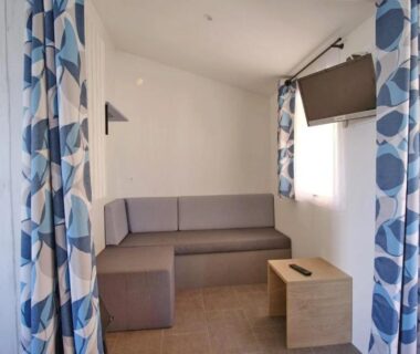 Salon avec canapé et télévision dans le mobil-home du ZEcamping 5 étoiles Parc Aqua