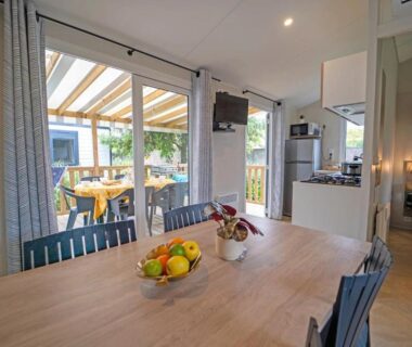 Séjour avec table, cuisine et terrasse couverte au ZEcamping 5 étoiles