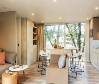 Intérieur de mobil-home salon et cuisine avec baie vitrée au ZEcamping 5 étoiles chiens acceptés animations parc aquatique