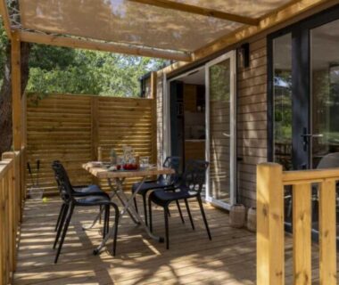 Terrasse en bois avec table et chaises sous pergola du mobile home au ZEcamping 5 étoiles