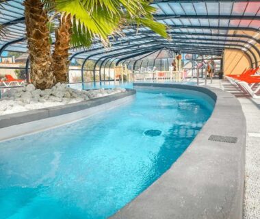 Piscine couverte avec toboggan et palmiers au ZEcamping parc aquatique pet friendly club enfant
