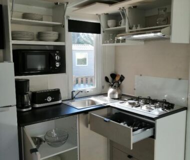 Coin cuisine avec plaque gaz micro-ondes et rangements dans le bungalow au soleil camping les dunes