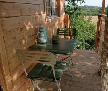 Terrasse en bois avec table chaises et lanterne dans la cabane perchée et le chêne