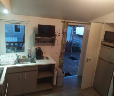 Coin cuisine et salon avec porte vitrée sur terrasse du camping 4**** proche mer