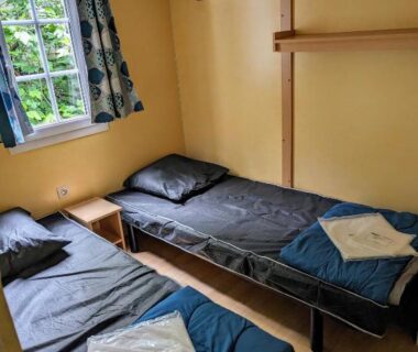Chambre avec deux lits simples et serviettes pliées dans le camping Youpendi