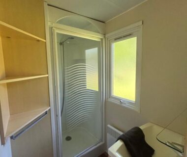 Salle de bain avec douche vitrée lavabo et fenêtre du camping Youpendi