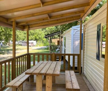 Terrasse couverte avec table en bois au camping Youpendi